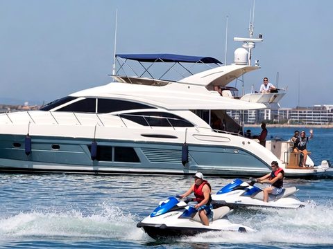 Two jet ski riders side by side passing a motor yacht