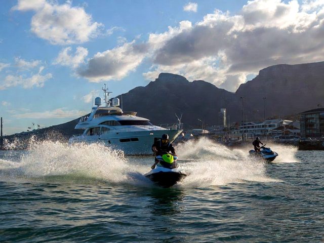 Jet ski heading towards the camera with Table Mountain and a superyacht behind